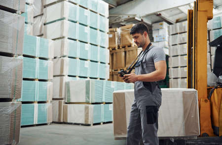 Storage worker in uniform and tablet in hands checks production.の写真素材