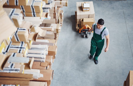 Top view of male worker in warehouse with pallet truck.