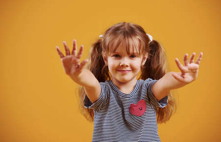 Cute little girl in casual clothes in the studio against yellow background.の写真素材