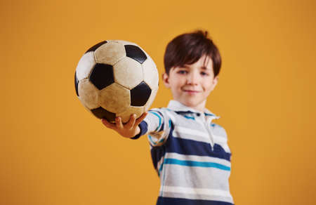Portrait of young soccer player with ball. Stands against yellow background.の写真素材