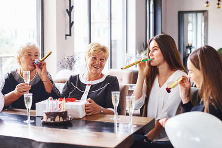 Senior woman with family and friends celebrating a birthday indoors.の写真素材