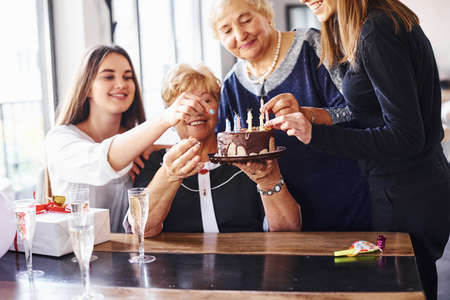 Senior woman with family and friends celebrating a birthday indoors.の写真素材