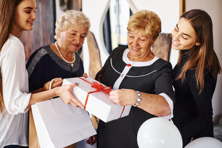 Senior woman with family and friends celebrating a birthday indoors.