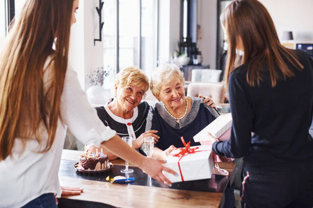 Senior woman with family and friends celebrating a birthday indoors.の写真素材