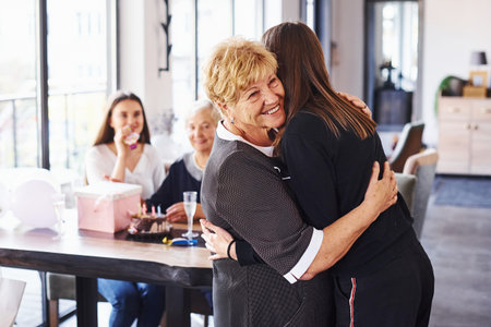 Embracing each other. Senior woman with family and friends celebrating a birthday indoors.