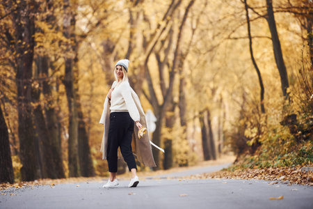 Portrait of young brunette that have a walk on road in autumn forest at daytime.