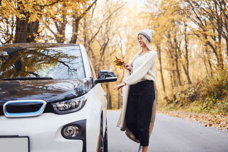Enjoying nature. Girl have autumn trip by car. Modern brand new automobile in the forest.の写真素材