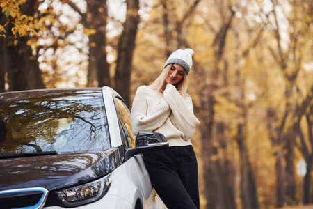 Girl have autumn trip by car. Modern brand new automobile in the forest.の写真素材