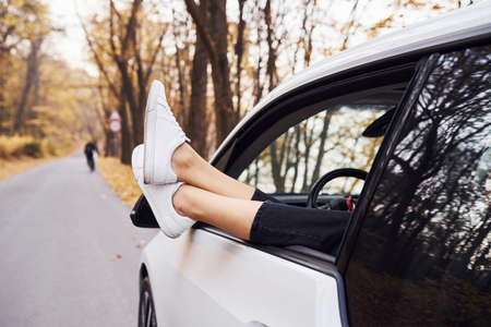 Womans legs is off the car window. Modern brand new automobile in the forest.の写真素材