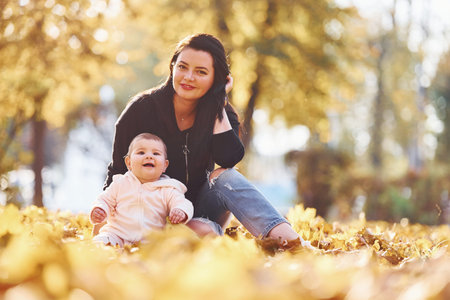Mother in casual clothes with her child is in the beautiful autumn park.