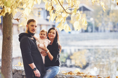 Cheerful family have a walk together with their child in the park.