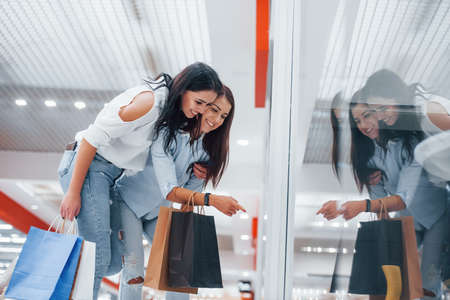 Looking through the glass. Two young women have a shopping day together in the supermarket.の写真素材