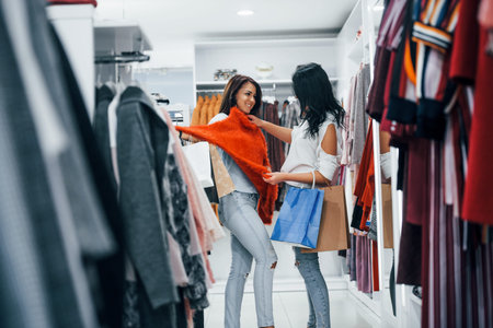 Looking for a warm clothes. Two young women have a shopping day together in the supermarket.