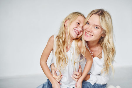 Closeness of the people. Mother with her daughter together in the studio with white background.