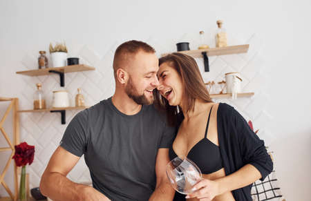 Woman in sexy black lingerie with her husband on the kitchen.の写真素材
