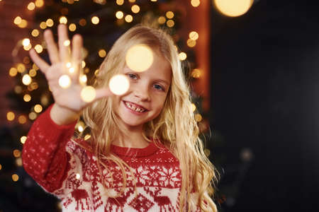 Cute little girl in near christmas tree indoors celebrating new year.の写真素材