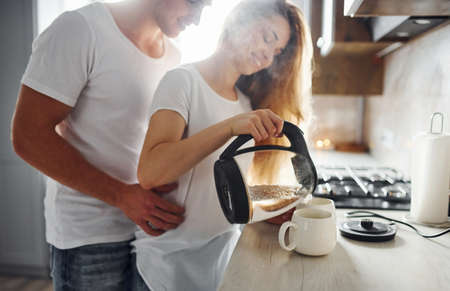 Young couple at morning together standing on the modern kitchen.の写真素材