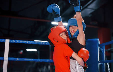 Portrait of two young boys in protective gloves celebrating victory on boxing ring.の写真素材