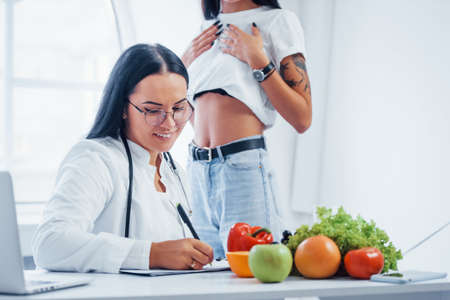 Female nutritionist gives consultation to patient indoors in the office.の写真素材