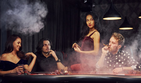 Group of elegant young people that playing poker in casino together.