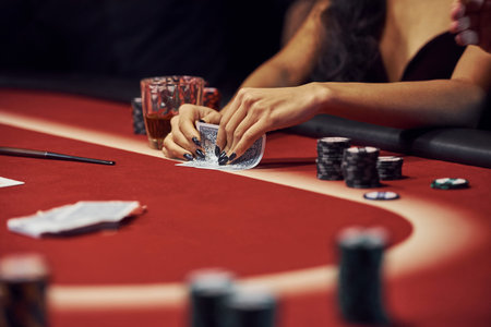 Close up view of womans hands. Girl plays poker game by table in casino.