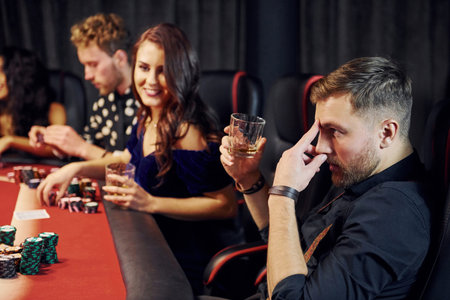 Group of elegant young people that playing poker in casino together.