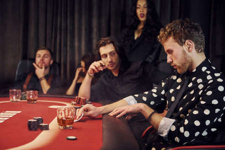 Side view of group of elegant young people that playing poker in casino together.の写真素材