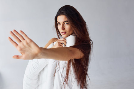 Stop gesture. Woman covering her body by towel in the studio against white background.
