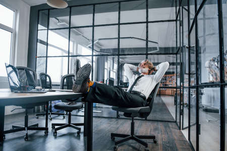 Senior businessman with grey hair and beard in formal clothes takes a break in the office.の写真素材