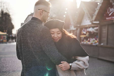 Cheerful multiracial couple embracing each other outdoors in the city. Asian girl with her caucasian boyfriend.の写真素材