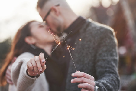 With sparklers in hands. Happy multiracial couple together outdoors in the city.