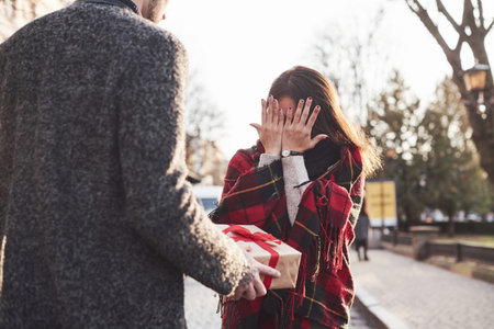 Time for presents. Holding gift box. Asian girl with her caucasian boyfriend.の写真素材