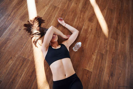 On the floor illuminated by light beams. Young sporty woman in sportswear resting.の写真素材