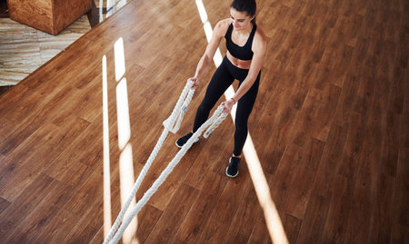 On the floor illuminated by light beams. Young sporty woman in sportswear doing fitness by using...