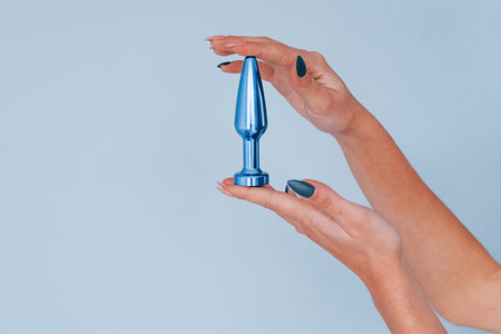 Woman holds blue sex toy in hands in the studio. Conveption of intimacy.