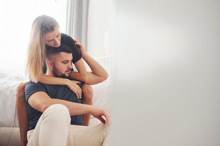 Young married couple have leisure together in bedroom at daytime.