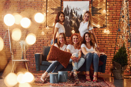 Cheerful women have fun by celebrating New Year holidays indoors of bright christmas decorated room.の写真素材