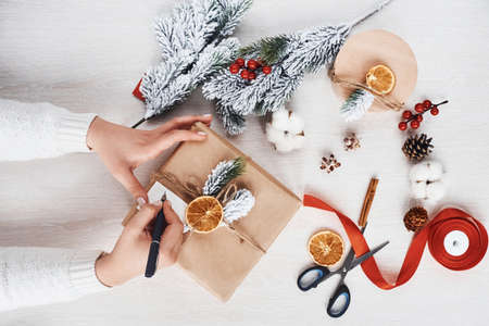 Girl making gift box. Top view of christmas festive frame with new year decorations.の写真素材
