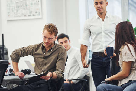 Young business people sitting by the table, talking and working together in the modern office.の写真素材