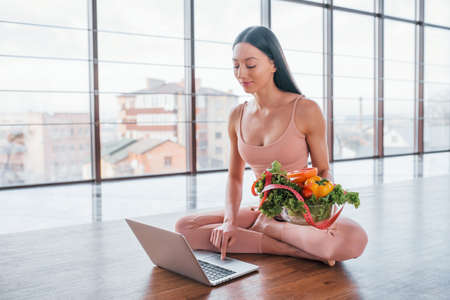 Sportive woman sitting on the table with laptop and healthy food.の写真素材