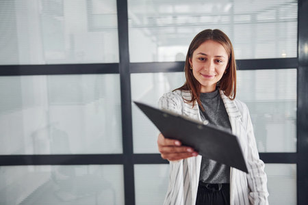 Portrait of young woman in white formal clothes that standing indoors.の写真素材