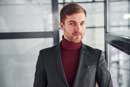 Young business man in luxury suit and formal clothes is indoors in the office.