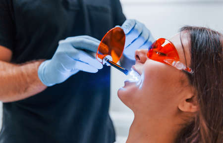 Beautiful woman in red protective glasses have a visit in the dentist clinic. Conception of stomatology.の写真素材