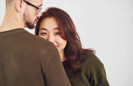 Happy multi ethnic couple in casual clothes is together indoors in the studio. Caucasian guy with asian girlfriend.の写真素材