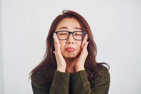 Portrait of happy asian young girl in eyewear that standing indoors in the studio against white background.の写真素材