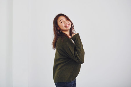 Portrait of happy asian young girl that standing indoors in the studio against white background.