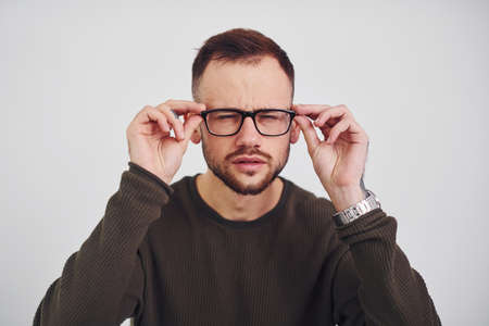 Young guy in sunglasses standing indoors against white background.の写真素材