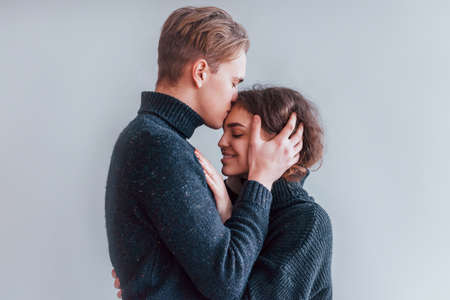Cute young couple embracing each other indoors in the studio.の写真素材