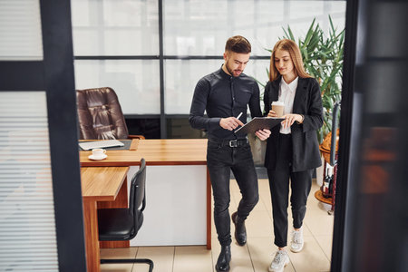 Woman and man in formal clothes with documents talking to each other in the office.の写真素材