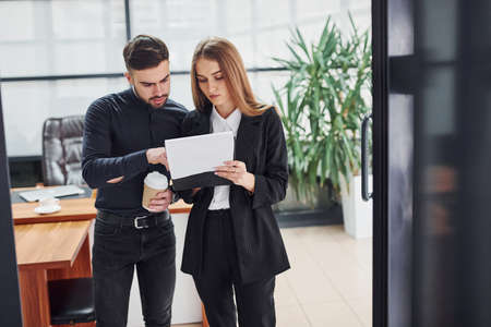 Woman and man in formal clothes with documents talking to each other in the office.の写真素材